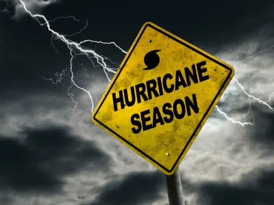 Yellow sign that says "Hurricane Season" With clouds and lightning in the background