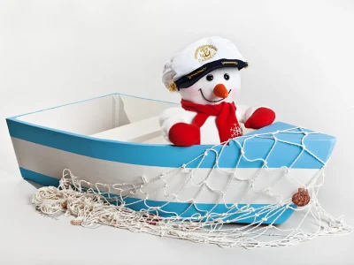 snowman in a captains hat sitting in a rowboat